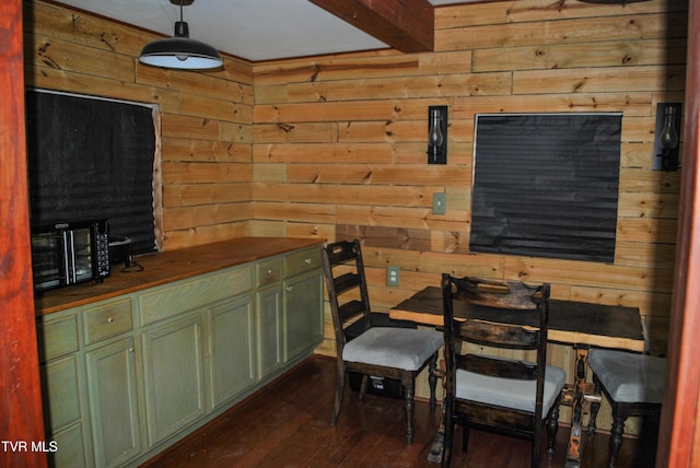 dining space with beam ceiling, wood walls, and dark hardwood / wood-style floors