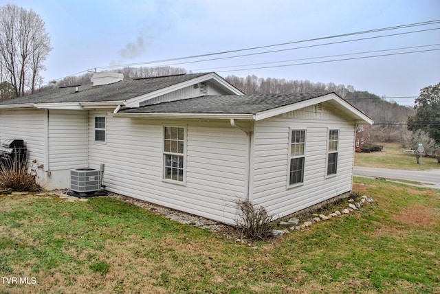 view of side of home featuring central AC and a yard