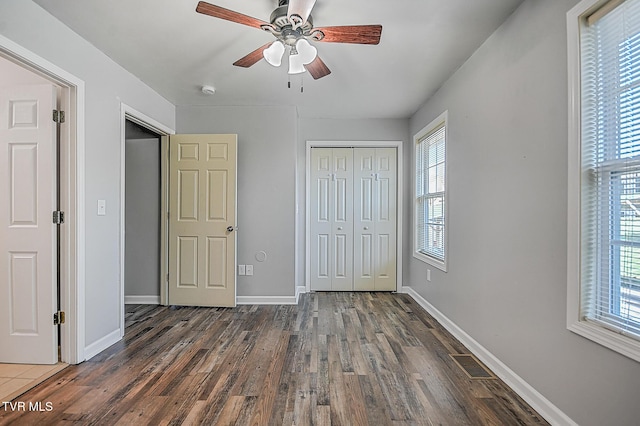 unfurnished bedroom featuring ceiling fan, a closet, multiple windows, and dark hardwood / wood-style floors