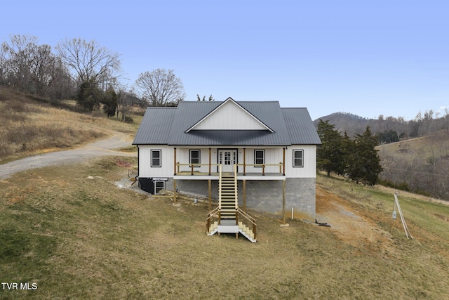 view of front of house with covered porch, a front yard, and a mountain view