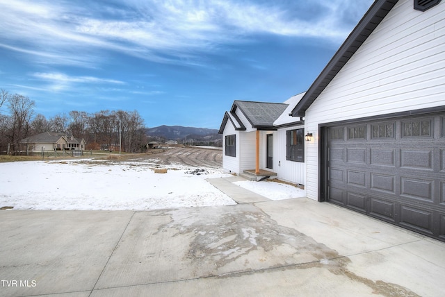 snow covered property featuring a mountain view and a garage