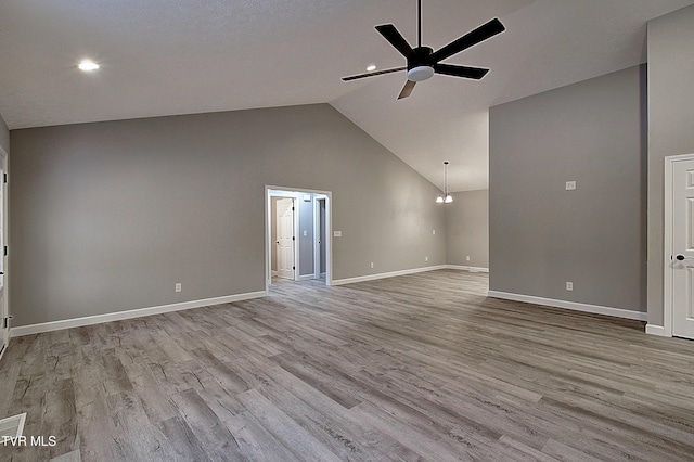 unfurnished living room with light hardwood / wood-style flooring, high vaulted ceiling, and ceiling fan with notable chandelier