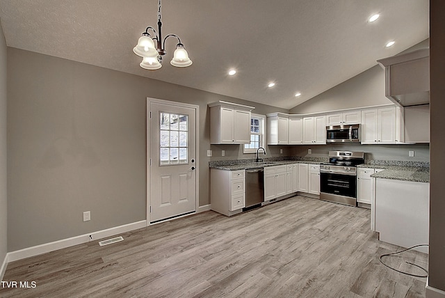 kitchen featuring sink, white cabinetry, vaulted ceiling, pendant lighting, and appliances with stainless steel finishes