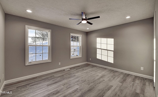 spare room featuring a textured ceiling, ceiling fan, and light hardwood / wood-style floors