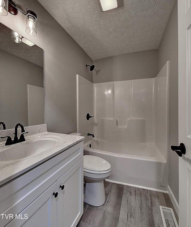 full bathroom featuring toilet, a textured ceiling, shower / bath combination, wood-type flooring, and vanity