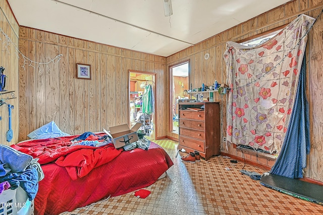 bedroom with ceiling fan and wood walls