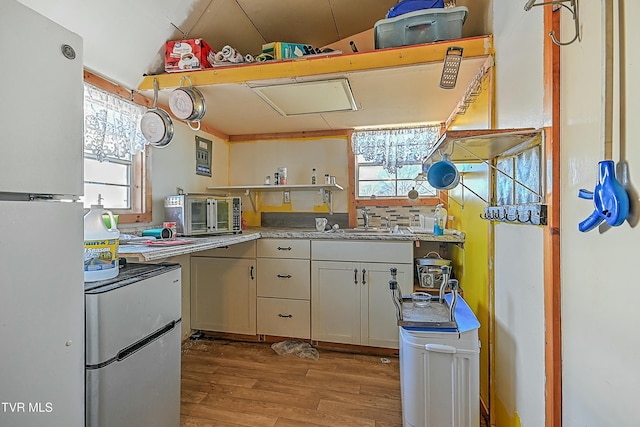 kitchen with white cabinetry, light hardwood / wood-style floors, stainless steel refrigerator, white refrigerator, and sink