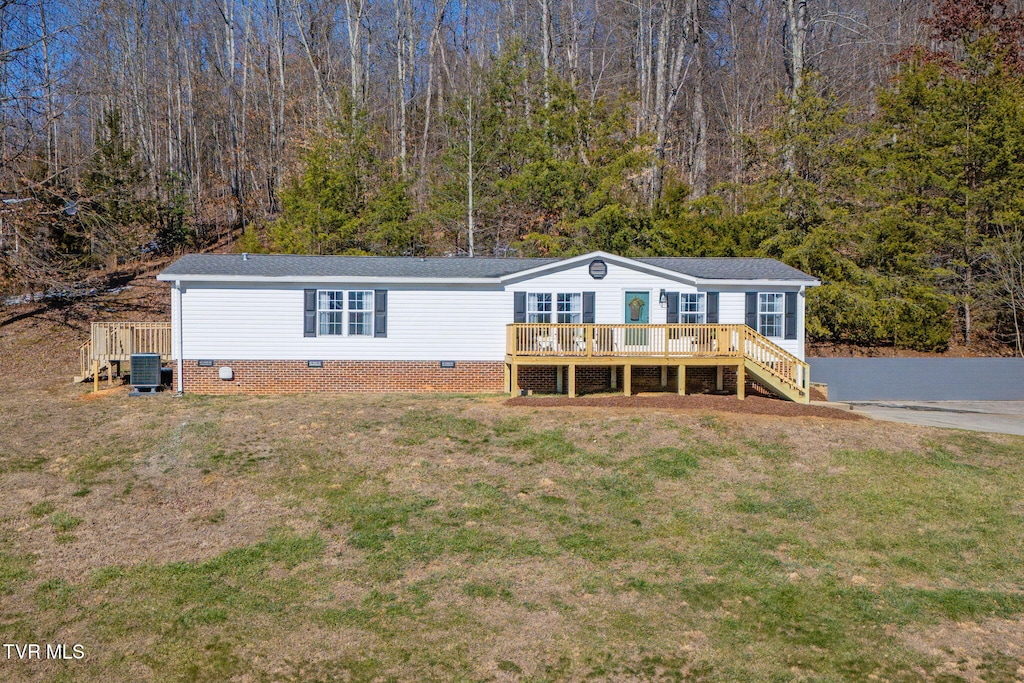 manufactured / mobile home featuring a wooden deck, cooling unit, and a front lawn