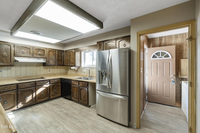 kitchen featuring light wood-type flooring, a textured ceiling, black appliances, dark brown cabinetry, and sink