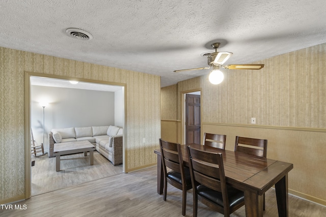 dining room with ceiling fan, wood-type flooring, and a textured ceiling