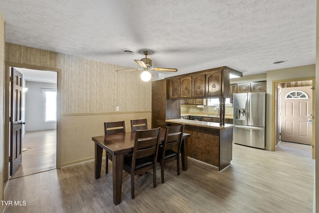 dining room featuring a textured ceiling, ceiling fan, light hardwood / wood-style flooring, and sink