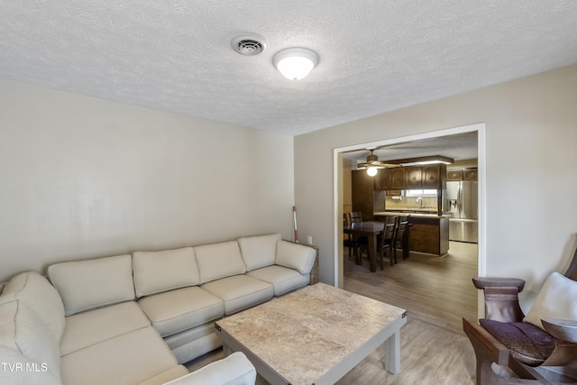 living room with light wood-type flooring, a textured ceiling, and sink