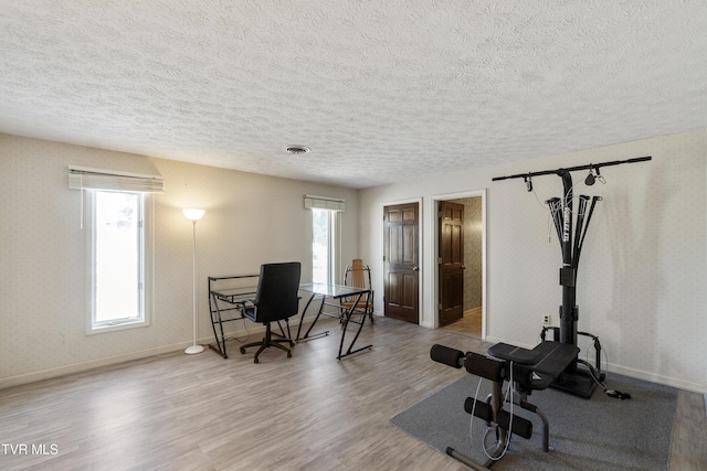 exercise area with a textured ceiling and light hardwood / wood-style flooring