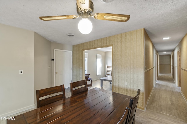 dining space with a textured ceiling, ceiling fan, and wood-type flooring