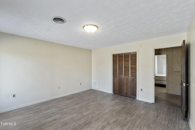 unfurnished bedroom featuring a textured ceiling, a closet, and hardwood / wood-style floors