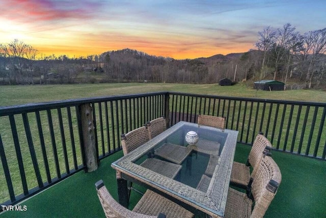 deck at dusk featuring a lawn