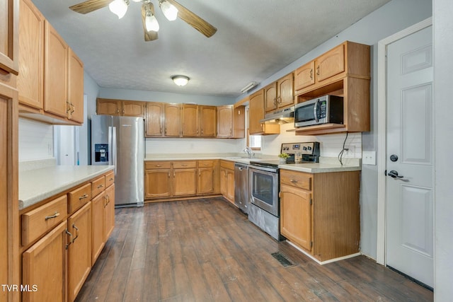 kitchen featuring ceiling fan, sink, stainless steel appliances, a textured ceiling, and dark hardwood / wood-style flooring