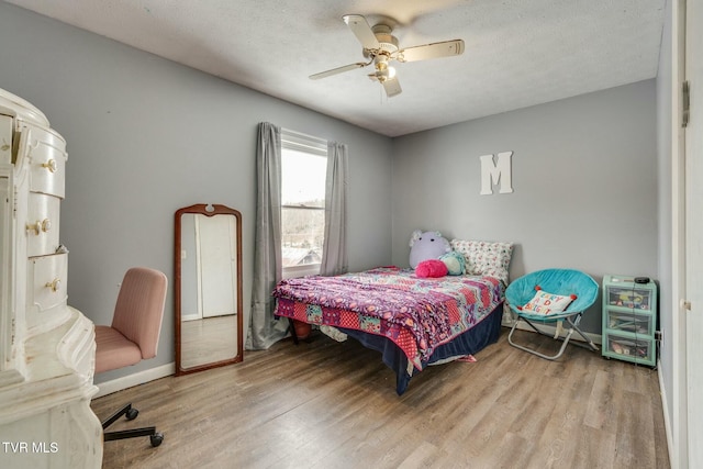 bedroom featuring ceiling fan, light hardwood / wood-style floors, and a textured ceiling