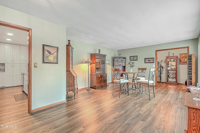 dining room featuring a textured ceiling and light hardwood / wood-style flooring