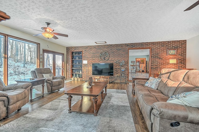 living room featuring ceiling fan, a textured ceiling, and hardwood / wood-style floors