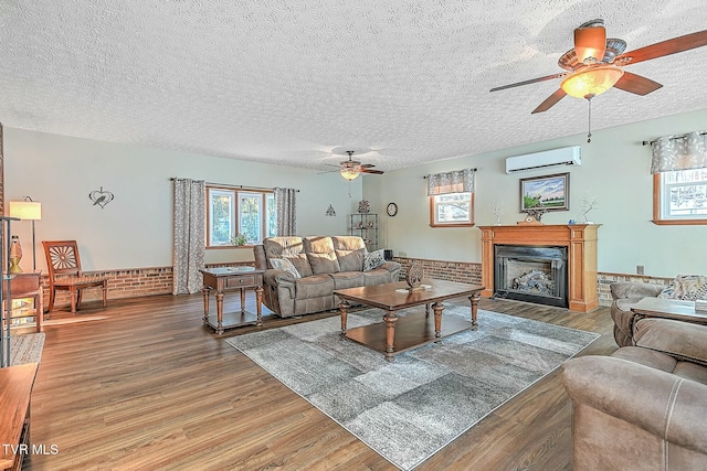 living room featuring hardwood / wood-style floors, ceiling fan, brick wall, a textured ceiling, and an AC wall unit