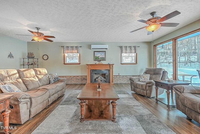 living room with a textured ceiling, ceiling fan, hardwood / wood-style flooring, and an AC wall unit