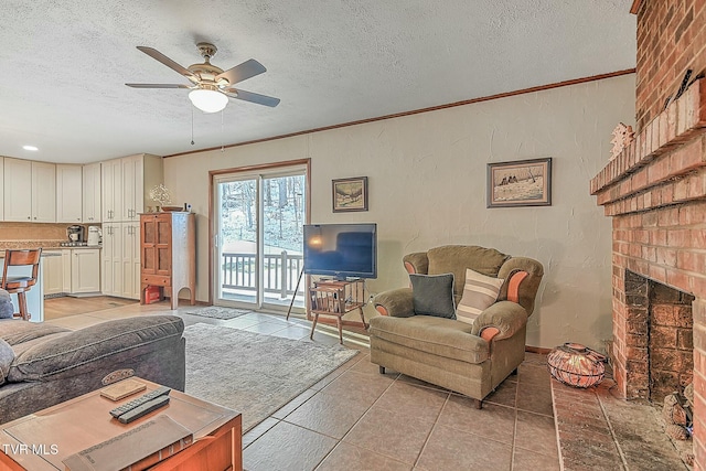 tiled living room featuring a textured ceiling, ceiling fan, and a brick fireplace