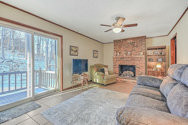 tiled living room featuring a textured ceiling, ceiling fan, and a brick fireplace