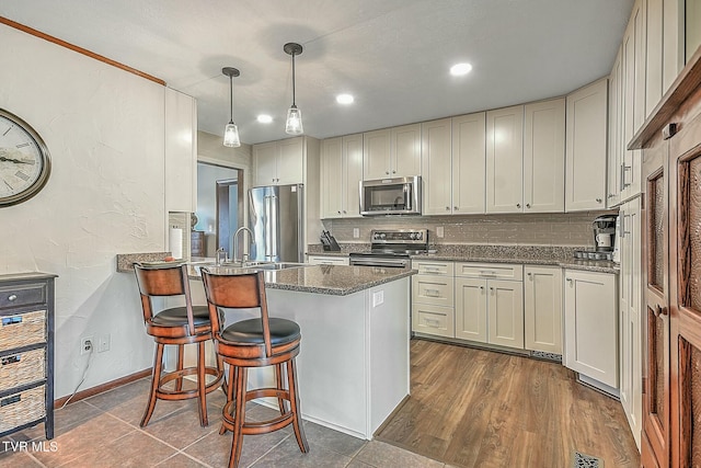 kitchen with hanging light fixtures, white cabinets, appliances with stainless steel finishes, and a breakfast bar area