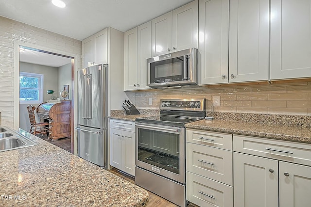 kitchen featuring dark hardwood / wood-style floors, light stone counters, stainless steel appliances, and white cabinetry