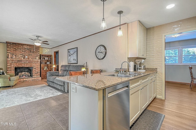 kitchen featuring a fireplace, sink, hanging light fixtures, ceiling fan, and stainless steel dishwasher