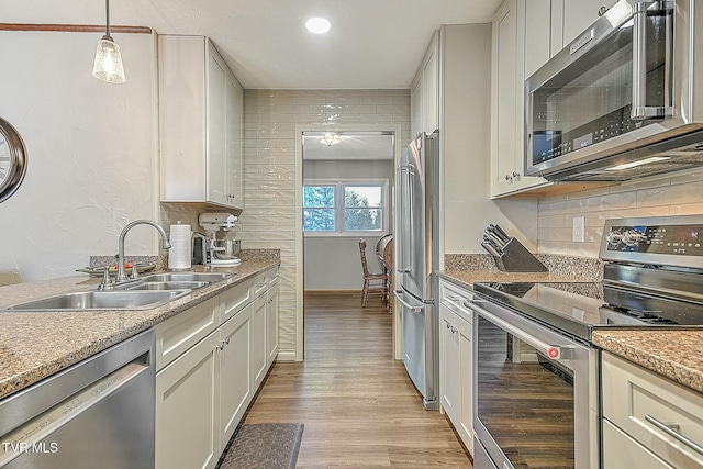 kitchen with decorative light fixtures, white cabinets, sink, and stainless steel appliances