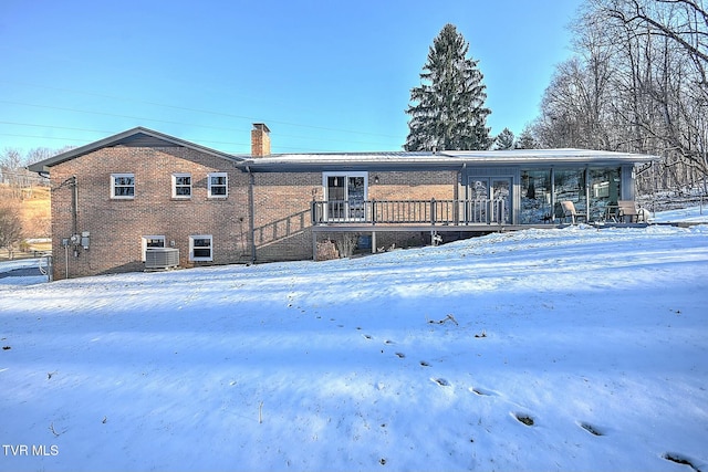 snow covered rear of property with a deck and cooling unit