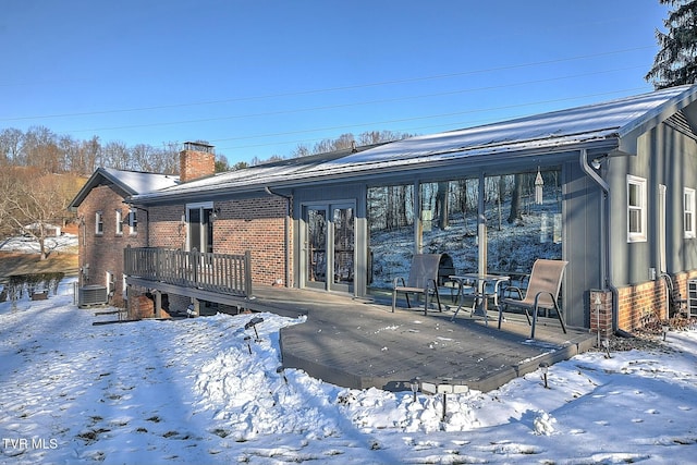 snow covered rear of property featuring a wooden deck and cooling unit