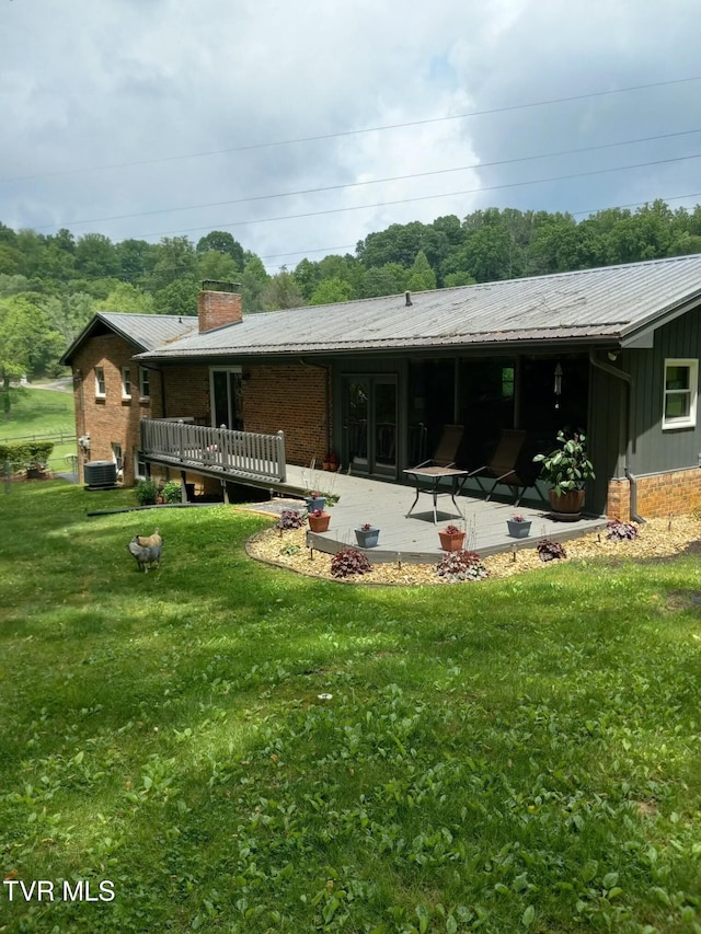 back of house with central AC, a wooden deck, a yard, and a patio