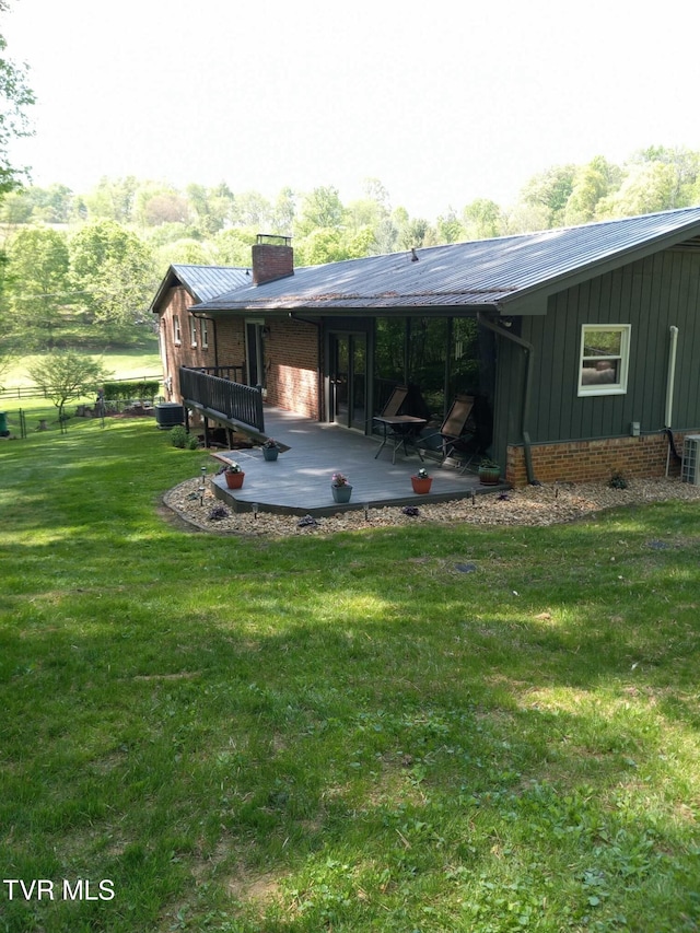 rear view of house featuring cooling unit and a lawn