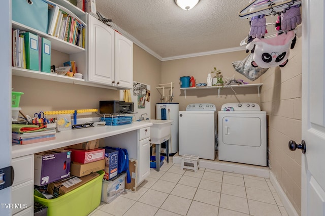 washroom featuring light tile patterned floors, washing machine and clothes dryer, a textured ceiling, cabinets, and ornamental molding