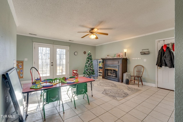 tiled dining area with ceiling fan, french doors, ornamental molding, and a textured ceiling