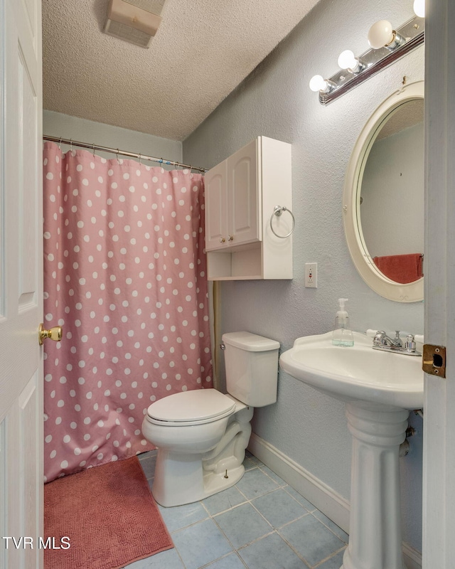 bathroom featuring a textured ceiling, tile patterned flooring, sink, toilet, and a shower with shower curtain