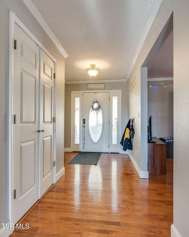 entryway featuring a textured ceiling, ornamental molding, and hardwood / wood-style flooring