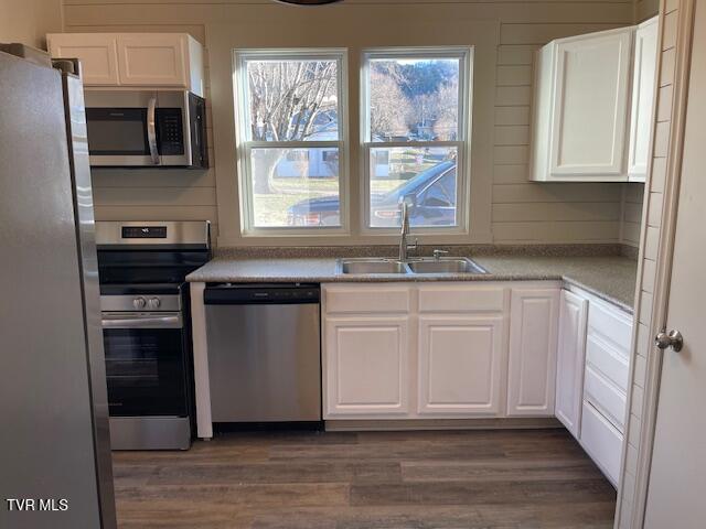 kitchen featuring appliances with stainless steel finishes, dark hardwood / wood-style flooring, white cabinets, and sink