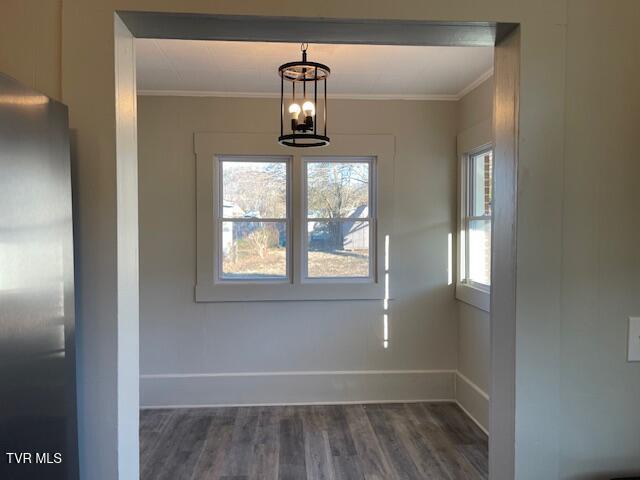 unfurnished dining area with a notable chandelier, crown molding, and dark hardwood / wood-style floors