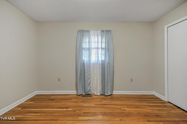 unfurnished room with a textured ceiling and hardwood / wood-style floors