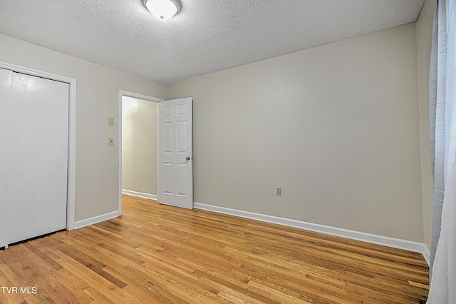 unfurnished bedroom featuring a textured ceiling, a closet, and light hardwood / wood-style floors