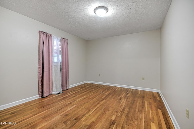 spare room with a textured ceiling and hardwood / wood-style floors