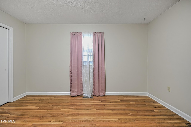 spare room with a textured ceiling and light wood-type flooring