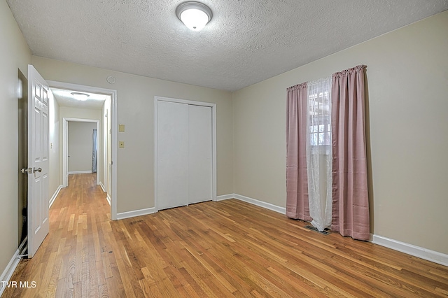 unfurnished bedroom with a closet, a textured ceiling, and light hardwood / wood-style flooring