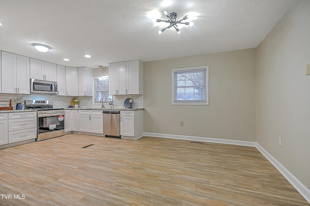 kitchen featuring white cabinets, stainless steel appliances, and light hardwood / wood-style flooring