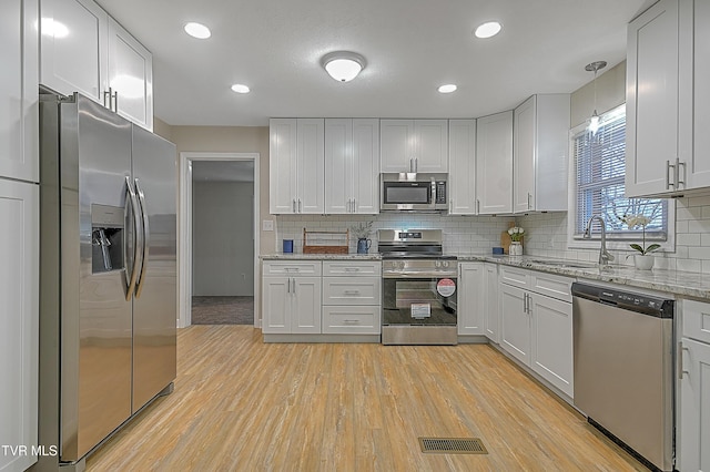 kitchen with sink, white cabinets, hanging light fixtures, and appliances with stainless steel finishes