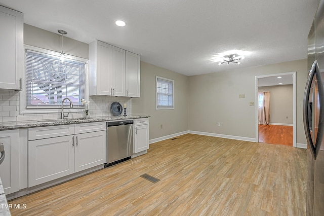 kitchen with backsplash, stainless steel appliances, white cabinets, and sink